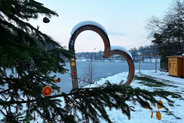 Durch ein Herz blickt man auf den Hammersee. Im Vordergrund ist eine geschmückte Tanne zu sehen.
