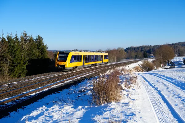 Die oberpfalzbahn fährt durch verschneite Landschaft.