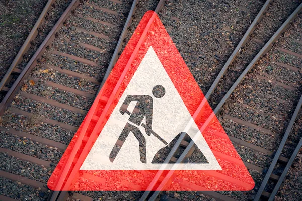 Rotes Warnschild für Gleisarbeiten vor mehreren Bahngleisen, Symbolbild für Bauarbeiten, Streckensperrungen und die Instandhaltung der Bahninfrastruktur.