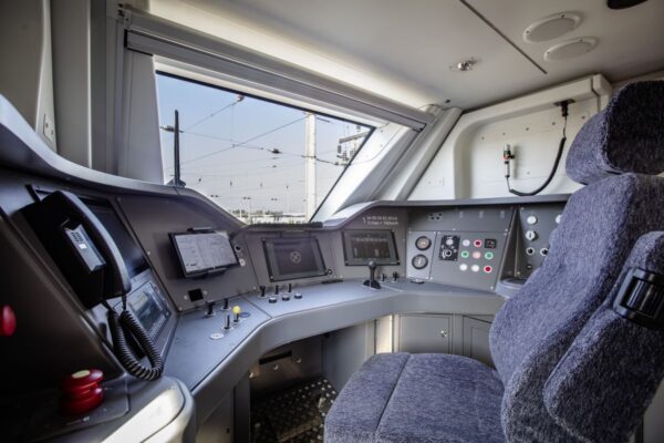 Das Bild zeigt einen Blick in den Führerstand eines Siemens Mireo-Zugs. Zu sehen sind der Fahrersitz sowie die Bedienkonsole.