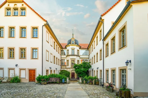 Blick auf einen großen Gebäudekomplex mit weißer Fassade, in dem sich der Bischofssitz befindet