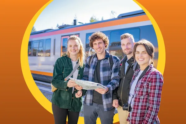 Eine Gruppe von Freunden hält eine Landkarte in der Hand und lacht in die Kamera. Im Hintergrund steht der trilex am Bahngleis.