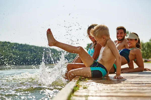 Eine Familie mit zwei Kindern sitzt in Badekleidung auf einem Steg.