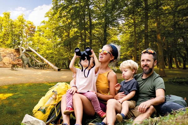 Collage im Vordergrund: Familie sitzt auf einer Wiese. Das Kind schaut durch ein Fernglas sowie im Hintergrund: Dinosaurierpark Kleinwelka