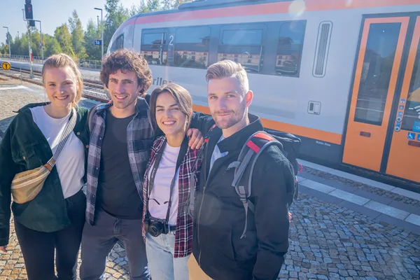Gruppe von 4 Personen steht am Bahnsteig vor einem trilex.