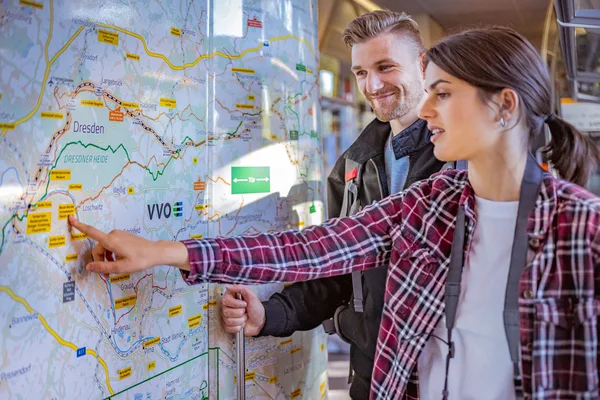 Zwei Personen stehen im Zug vor der Wanderkarte und planen ihre Tour.