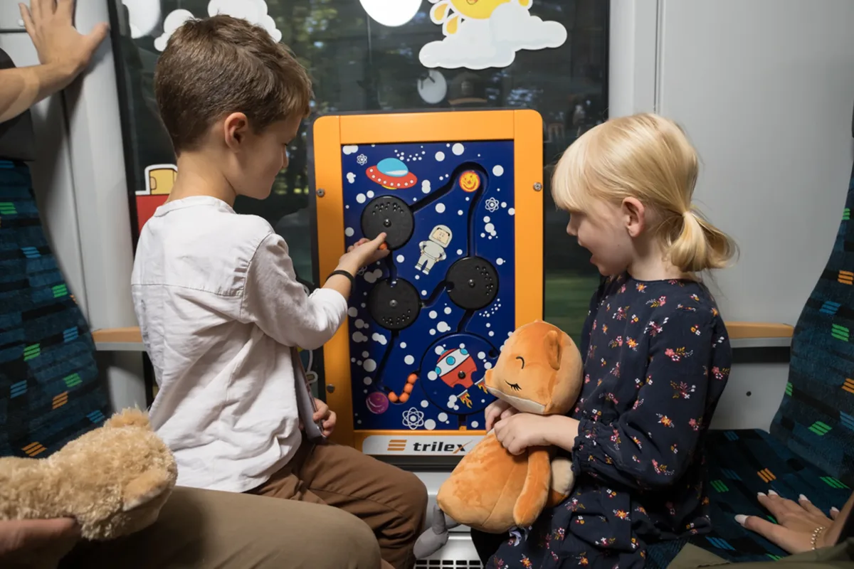Zwei Kinder sitzen im trilex-Kinderabteil und spielen an der Interaktionswand.