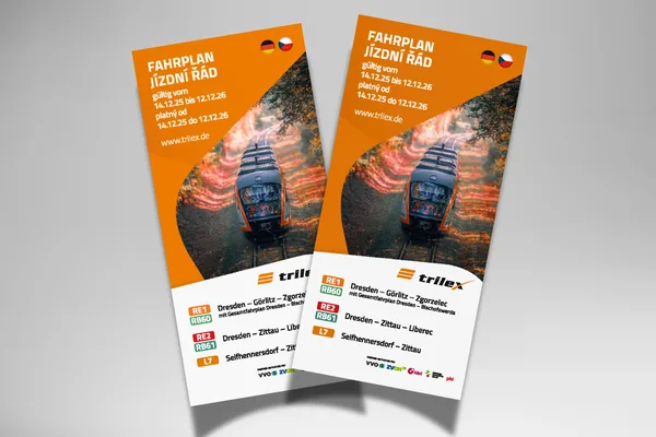 Auf grauen Hintergrund liegen zwei gedruckte Fahrplanbroschüren des trilex für das Fahrplanjahr 2025-2026