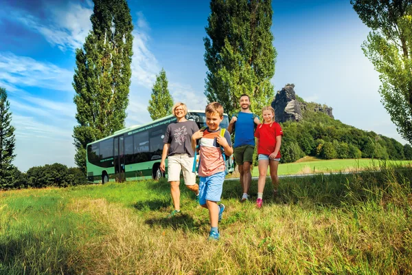 Eine Familie beginnt in der Sächsischen Schweiz eine Wanderung. Im Hintergrund sieht beim einen grünen Bus.