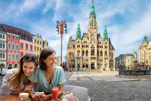 Blick auf eine Fotocollage mit Reisenden im Vordergrund und im Hintergrund die Altstadt von Liberec