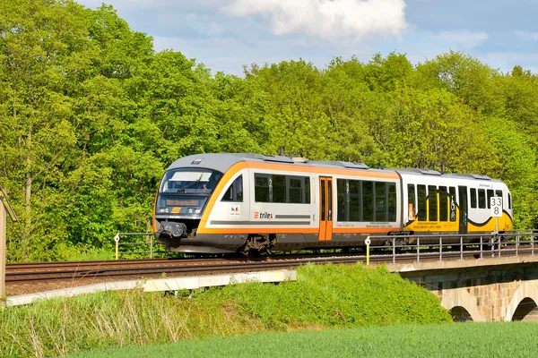 Über die Eisenbahnbrücke bei Pommritz rollt ein teilbekleber trilex-Triebwagen in den Farben des trilex und der polnisch KD.