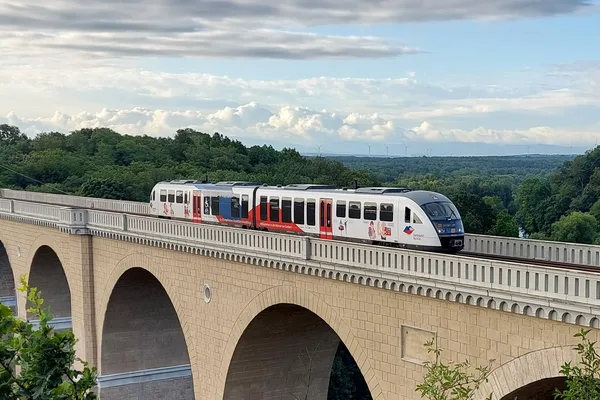 Ein trilex-Triebwagen fährt über das Neißeviadukt bei Görlitz. Er ist in weiß-blau-rot Beklebt und steht symbolisch für die sorbische Minderheit der Oberlausitz.