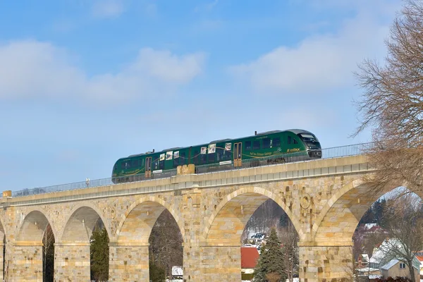 Ein trilex-Triebwagen fährt über das Neißeviadukt bei Zittau und erstrahlt in einer dunkelgrünen Sonderbeklebung.