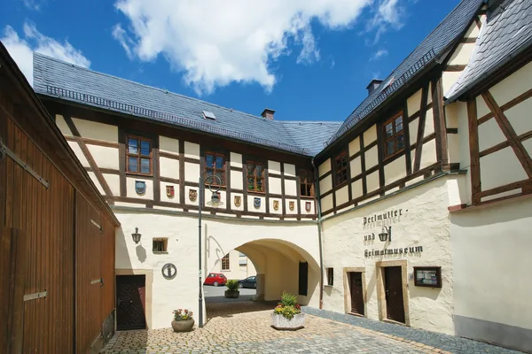 Ein Innenhof mit eines Fachwerk-Hofgebäudes mit einem Bogen als Durchgang und der Beschriftung Perlmutter- und Heimatmuseum in alten Buchstaben an der Fassade.