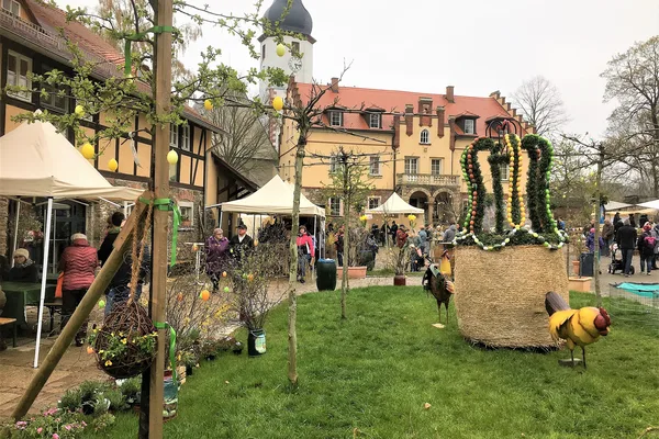 Das Bild zeigt einen Hof mit Ostermarkt im Gut Neumark. Es sind verschiedene Stände zu sehen und ein Osterkranz auf einem Heuballen.