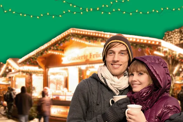 Ein junges Paar trinkt auf dem Weihnachtsmarkt ein heißes Getränk.