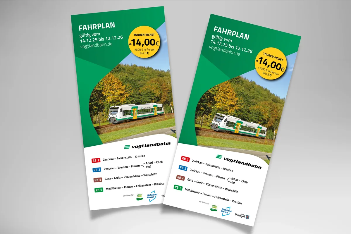 Zwei Flyer mit dem Titel „FAHRPLAN“ liegen auf einer grauen Fläche. Beide zeigen ein Foto einer Landschaft mit Fluss und Bäumen unter blauem Himmel mit Wolken. Auf den Flyern steht „FAHRPLAN gültig vom 14.12.25 bis 12.12.26“, dazu die Website „vogtlandbahn.de“. Ein gelber Kreis hebt den Preis „14 € + 9 € je Mitfahrer“ hervor. Unten sind Logos von „Vogtland Verkehr“, "Freistaat Thüringen" und „BEG“ sowie die Angaben der 4 Vogtlandbahn-Linien RB 1, RB 2, RB 4 und RB 5.