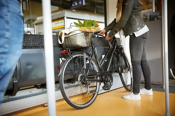 Das Bild zeigt eine Reisende mit einem Fahrrad im Mehrzweckbereich der Vogtlandbahn. Hier befestigt sie mit Hilfe der Gurte ihr Fahrrad.