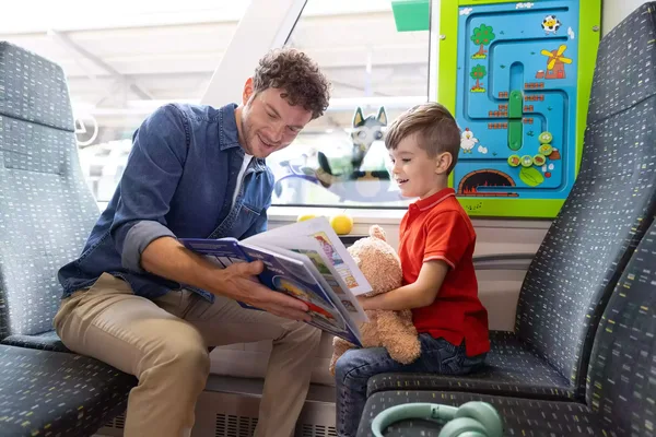 Das Bild zeigt einen Vater mit seinem Jungen in der Kinderspielecke in der Vogtlandbahn. Sie schauen sich zusammen ein Buch an.