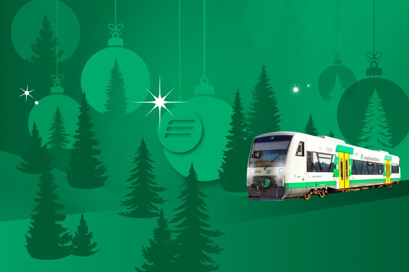 vogtlandbahn-Zug fährt durch eine grafisch dargestellte, winterliche Landschaft mit Tannenbäumen und Weihnachtsdekoration.