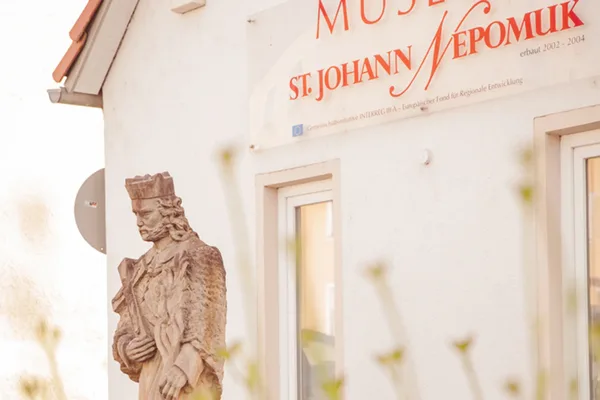 Eine kleine Statue vor der Fassade des Nepomuk-Museums.