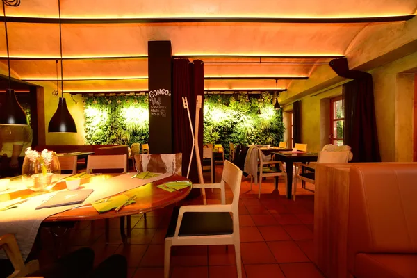 Ein Restaurant mit einzelnen Tischen und einer bepflanzten Wand.