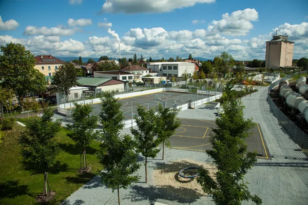 Blick von oben auf einen eingezäunten Sportplatz, einzelne Spielgeräte und einen Skatepark.