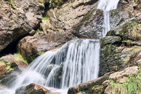 Ein Wasserfall fließt an großen Felsbrocken entlang nach unten.