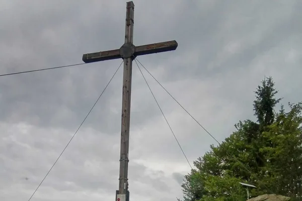 Ein Gipfelkreuz vor bewölktem Himmel.