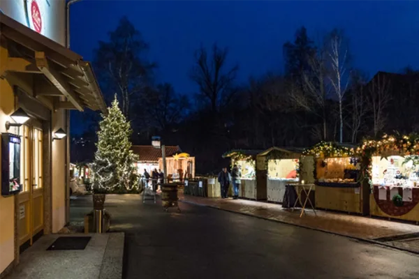 Weihnachtsmarktbuden entlang einer Straße im Dunkeln.