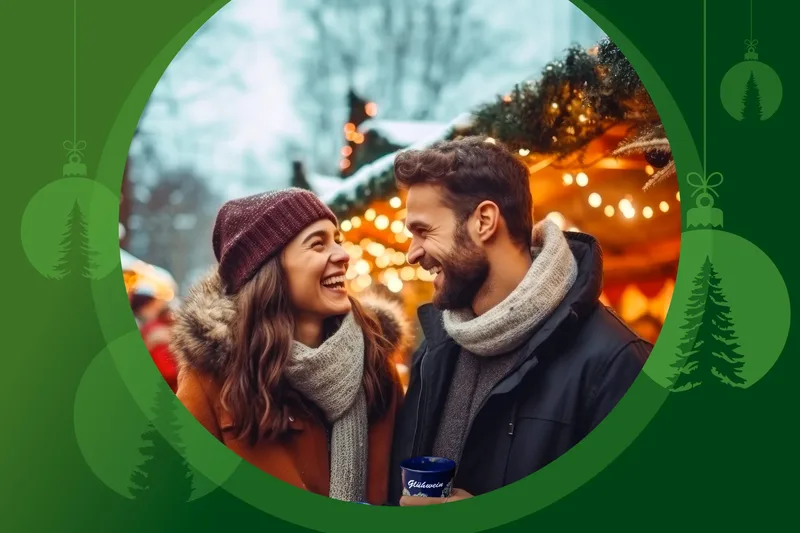 Zwei Personen lächeln sich an. Im Hintergrund ist ein Weihnachtsmarkt zu erkennen.