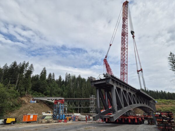 Die komplette neue Nagerlbrücke hängt an einem Spezialkran. Im Hintergrund die alte Brücke.