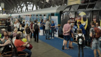 Auf diesem Bild sehen Sie zahlreiche Besucher:innen am Bahnsteig und dem Infostand der Länderbahn.