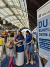 Auf diesem Bild sehen Sie zwei Mitarbeiterinnen der Länderbahn, die eine Besucherin am Infostand beraten.