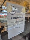 Auf diesem Bild sehen Sie ein an einer Scheibe angebrachtes Plakat, das auf den Kinderabteil im Zug hinweist.