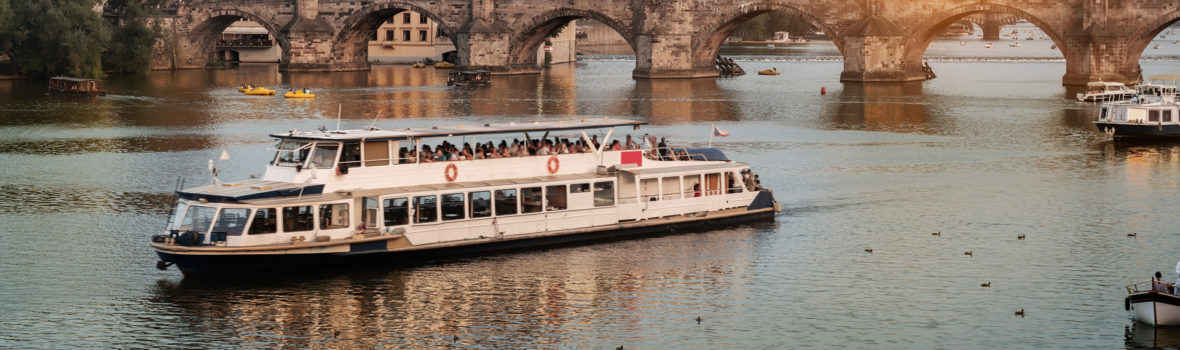 Ausflugsschiff auf der Moldau vor der Prager Altstadt im romantischen Sonnenuntergang