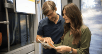 Zwei Personen schauen auf den Fahrplan im Zug.