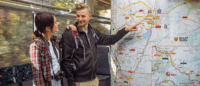 Zwei Personen schauen auf eine große Wanderkarte im Zug.