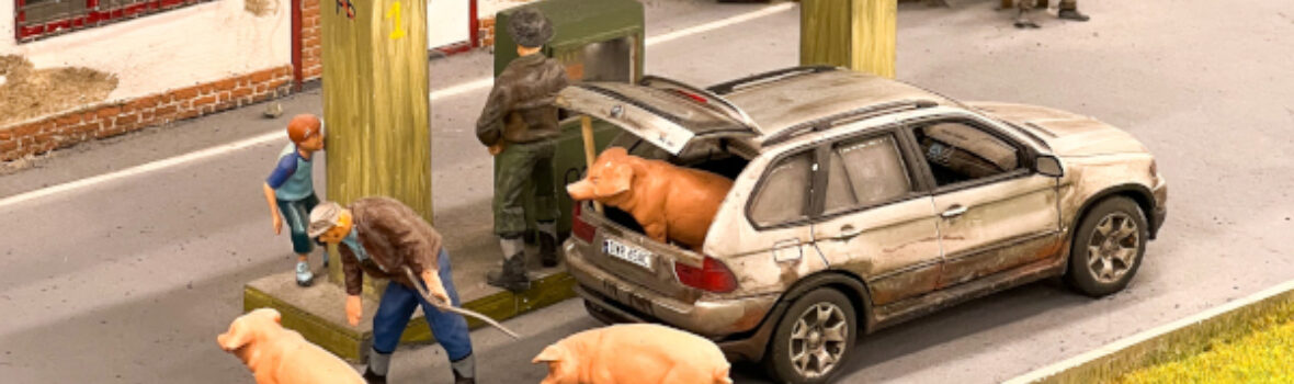 Ansicht der Miniaturwelt Kolejkowo. Man sieht ein Schweinetransport in einem Auto an einer Tankstelle.