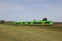 Waldbahn faehrt auf 4 verschiedenen linien Die waldbahn fährt auf dem Gleis neben einer großen Wiese